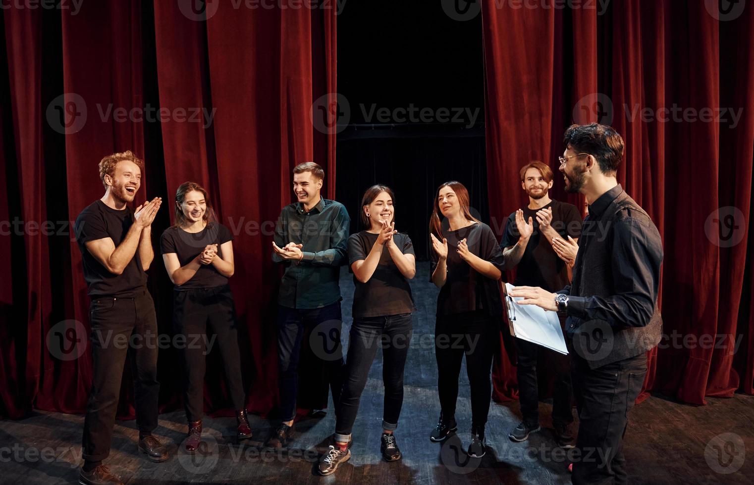 el hombre está practicando su papel. grupo de actores con ropa de color oscuro ensayando en el teatro foto