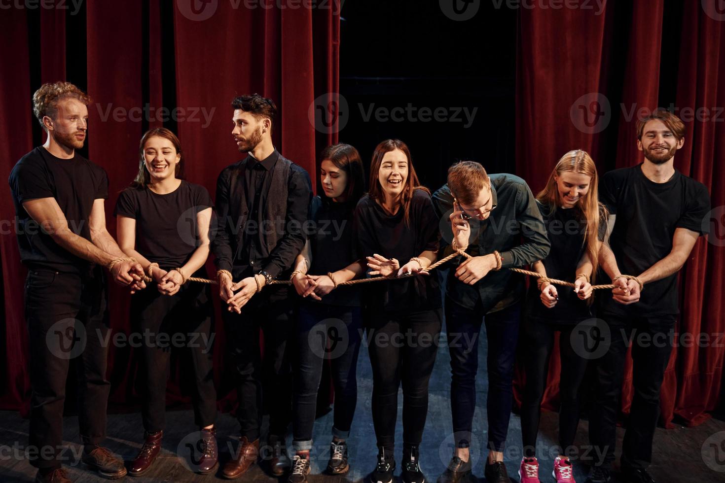 With rope in hands. Group of actors in dark colored clothes on rehearsal in the theater photo