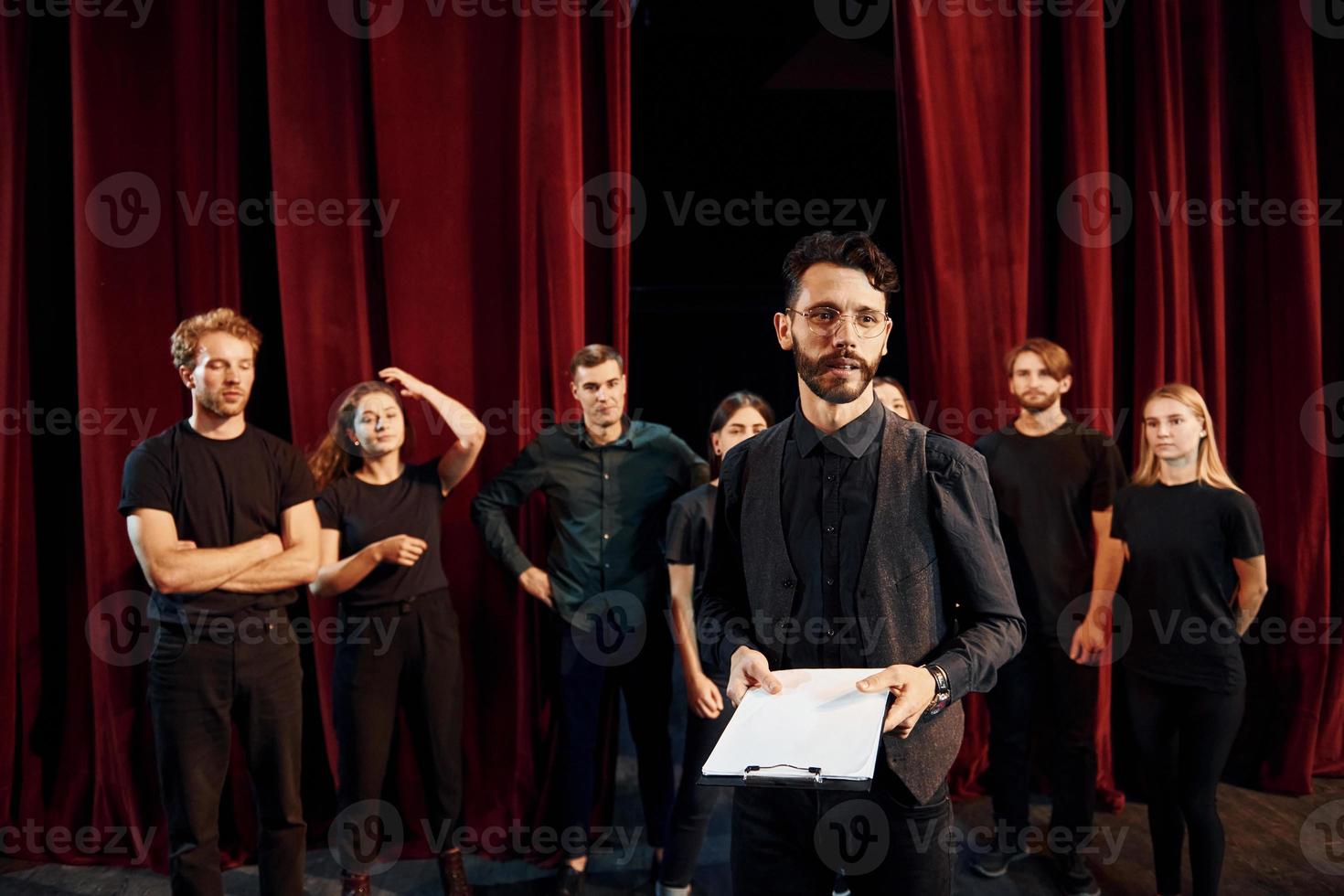 Expressionalible guy practicing his role. Group of actors in dark colored clothes on rehearsal in the theater photo
