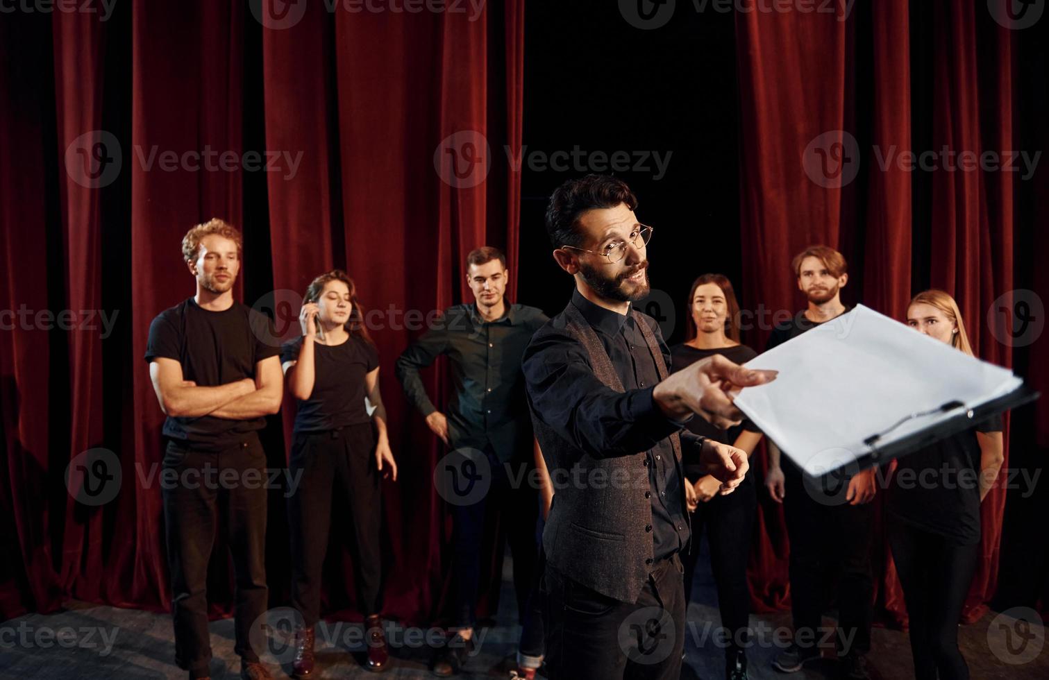 Expressionalible guy practicing his role. Group of actors in dark colored clothes on rehearsal in the theater photo