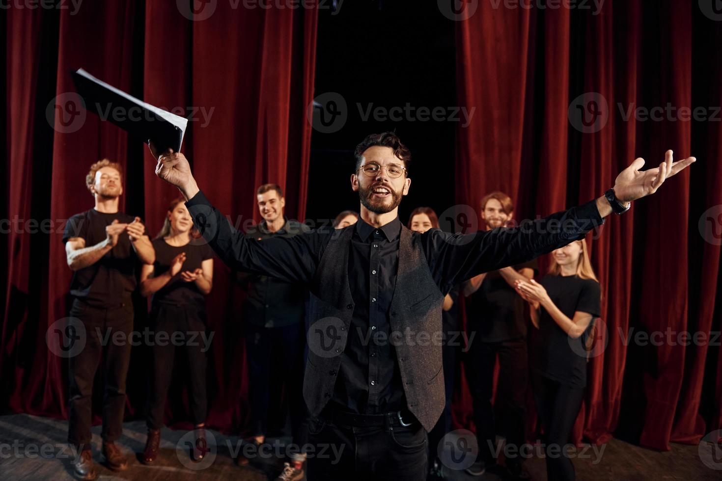 Man is practicing his role. Group of actors in dark colored clothes on rehearsal in the theater photo