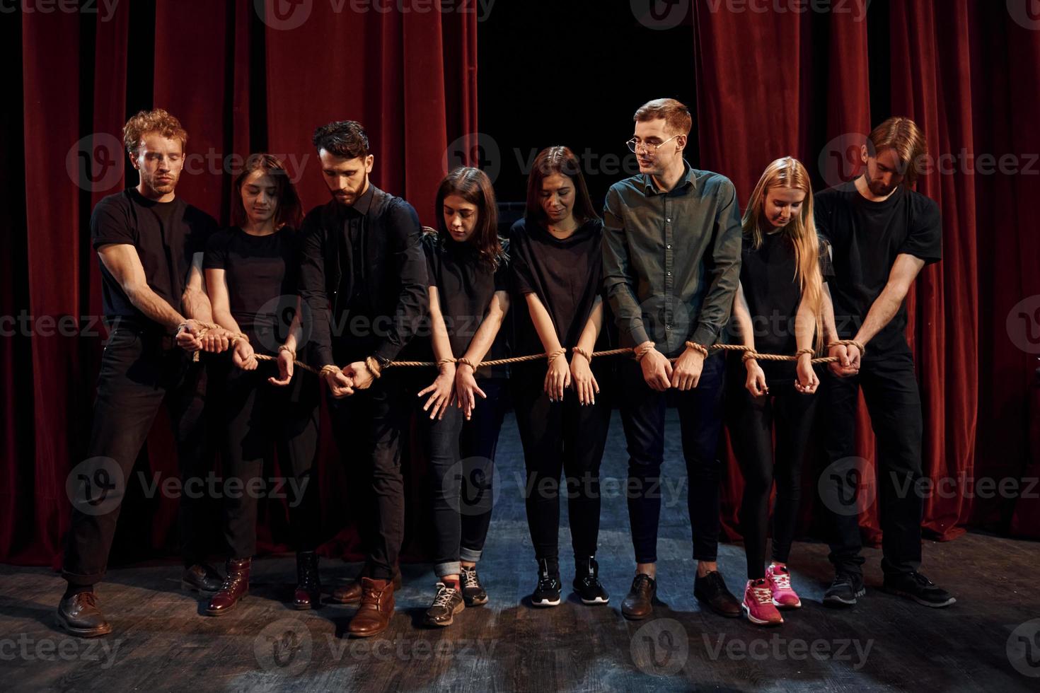 With rope in hands. Group of actors in dark colored clothes on rehearsal in the theater photo