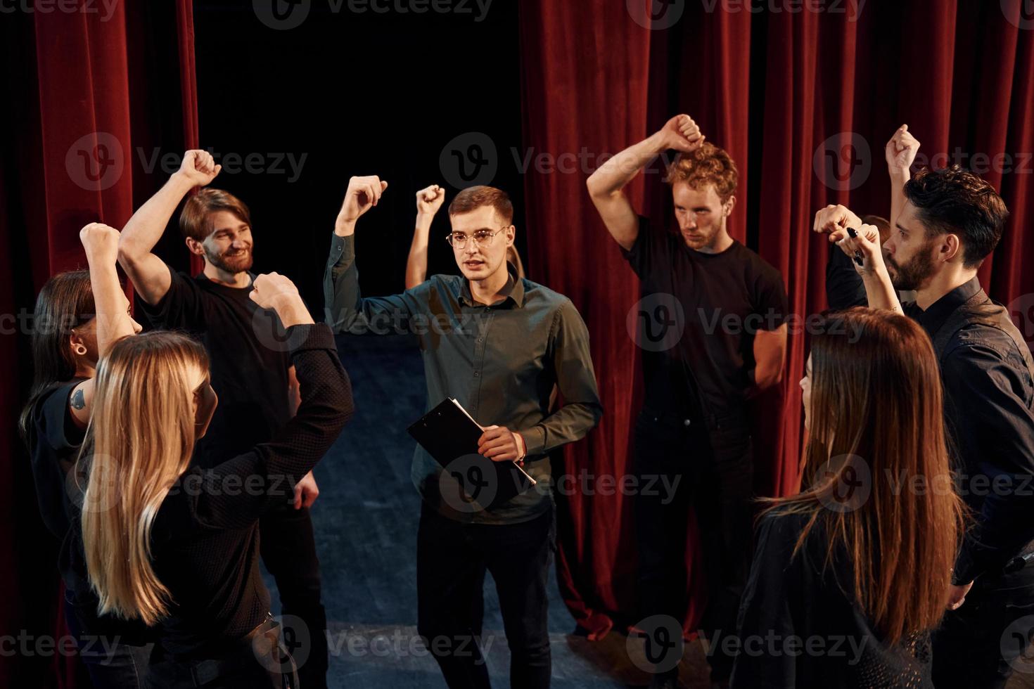 Practice in progress. Group of actors in dark colored clothes on rehearsal in the theater photo