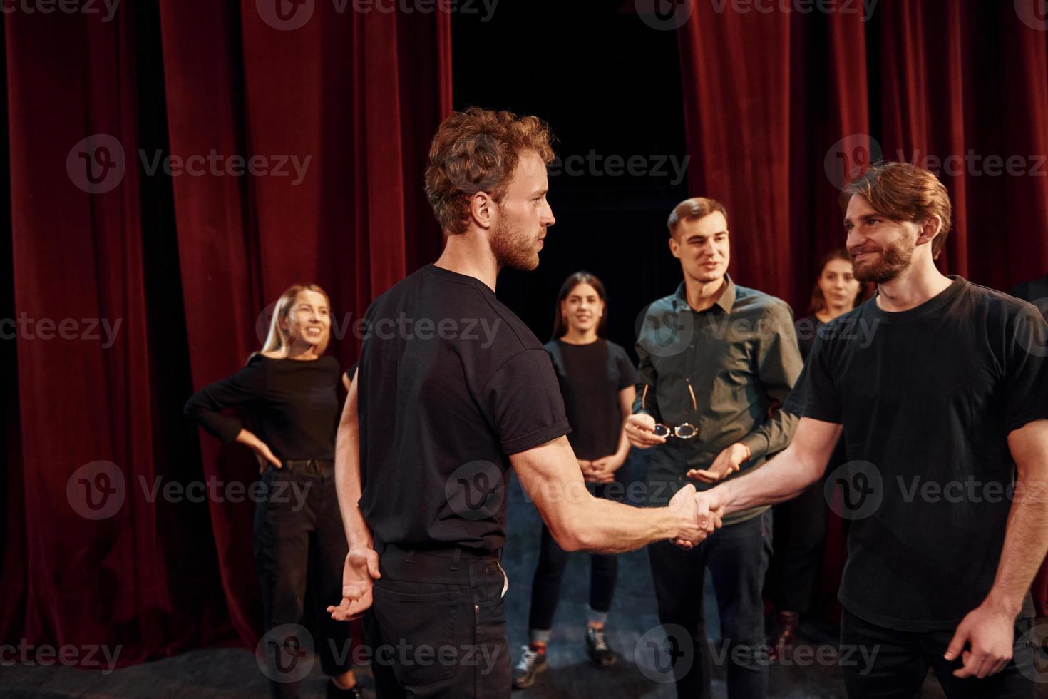 Eye contact practice. Group of actors in dark colored clothes on rehearsal in the theater photo