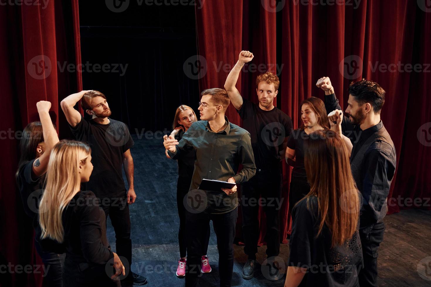 Practice in progress. Group of actors in dark colored clothes on rehearsal in the theater photo