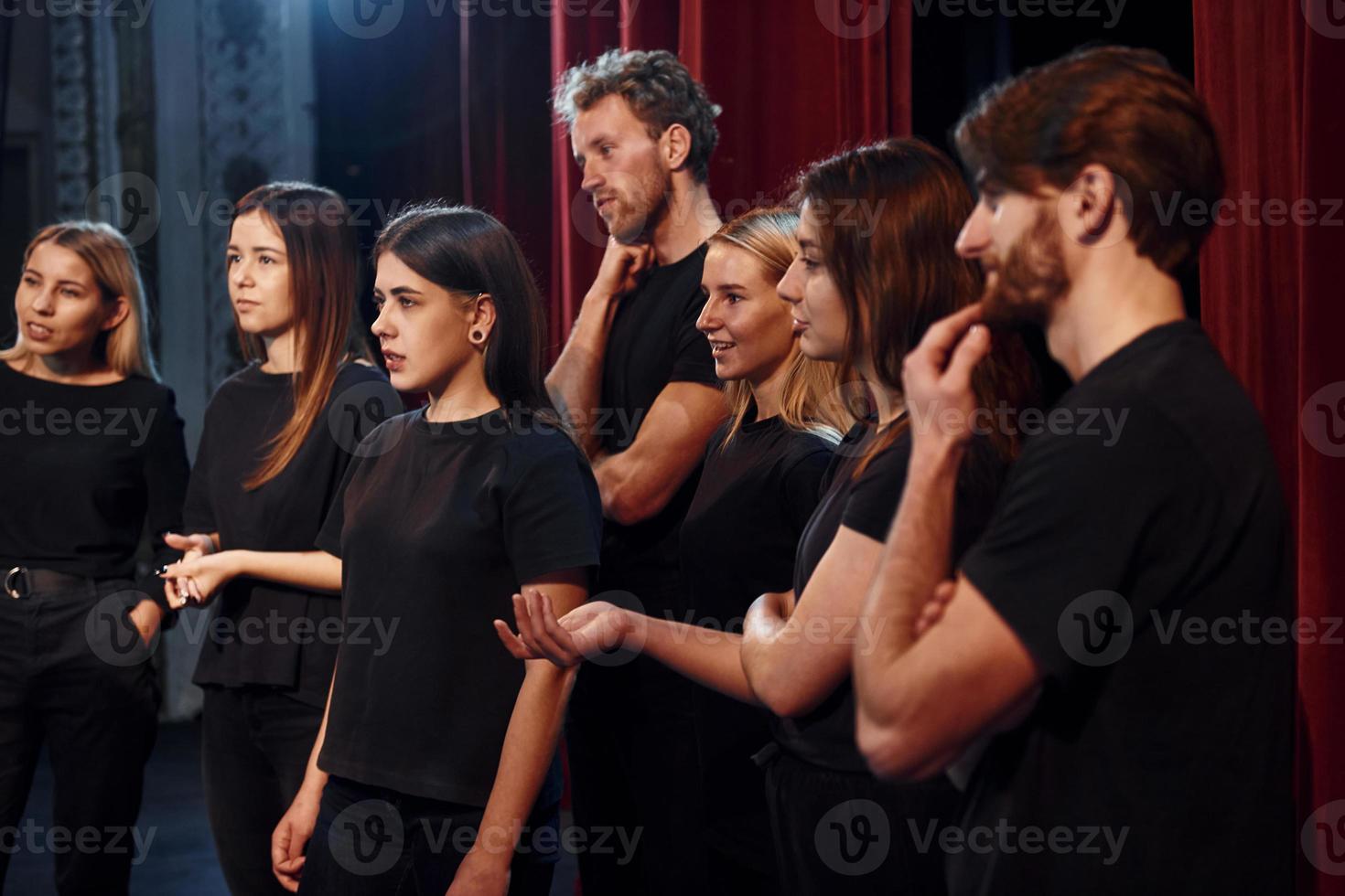 vista lateral. grupo de actores con ropa de color oscuro ensayando en el teatro foto