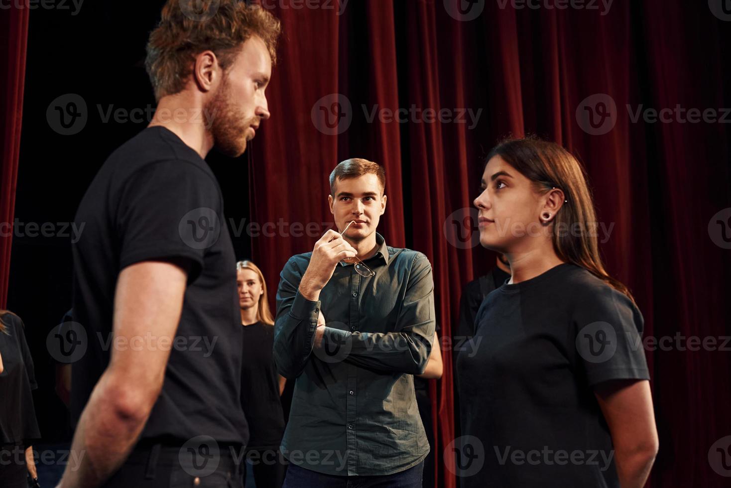 Two people talking. Group of actors in dark colored clothes on rehearsal in the theater photo