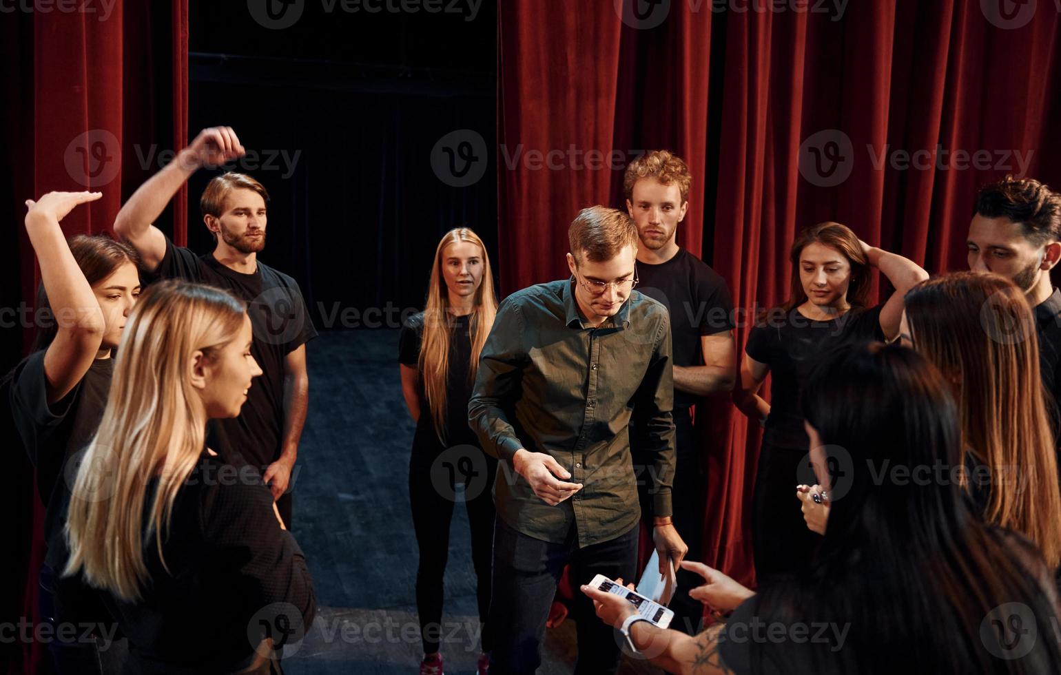 práctica en curso. grupo de actores con ropa de color oscuro ensayando en el teatro foto