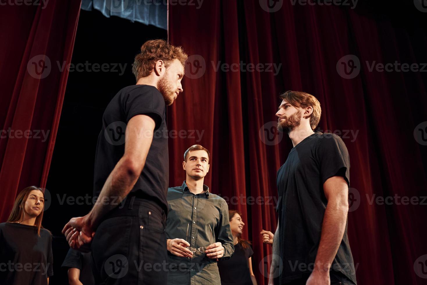 Two people talking. Group of actors in dark colored clothes on rehearsal in the theater photo