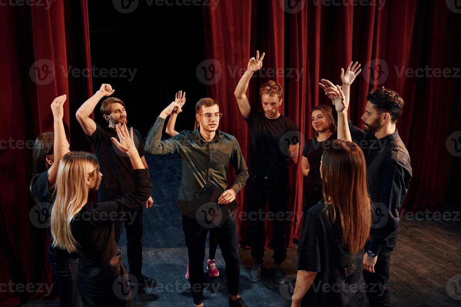 práctica en curso. grupo de actores con ropa de color oscuro ensayando en el teatro foto