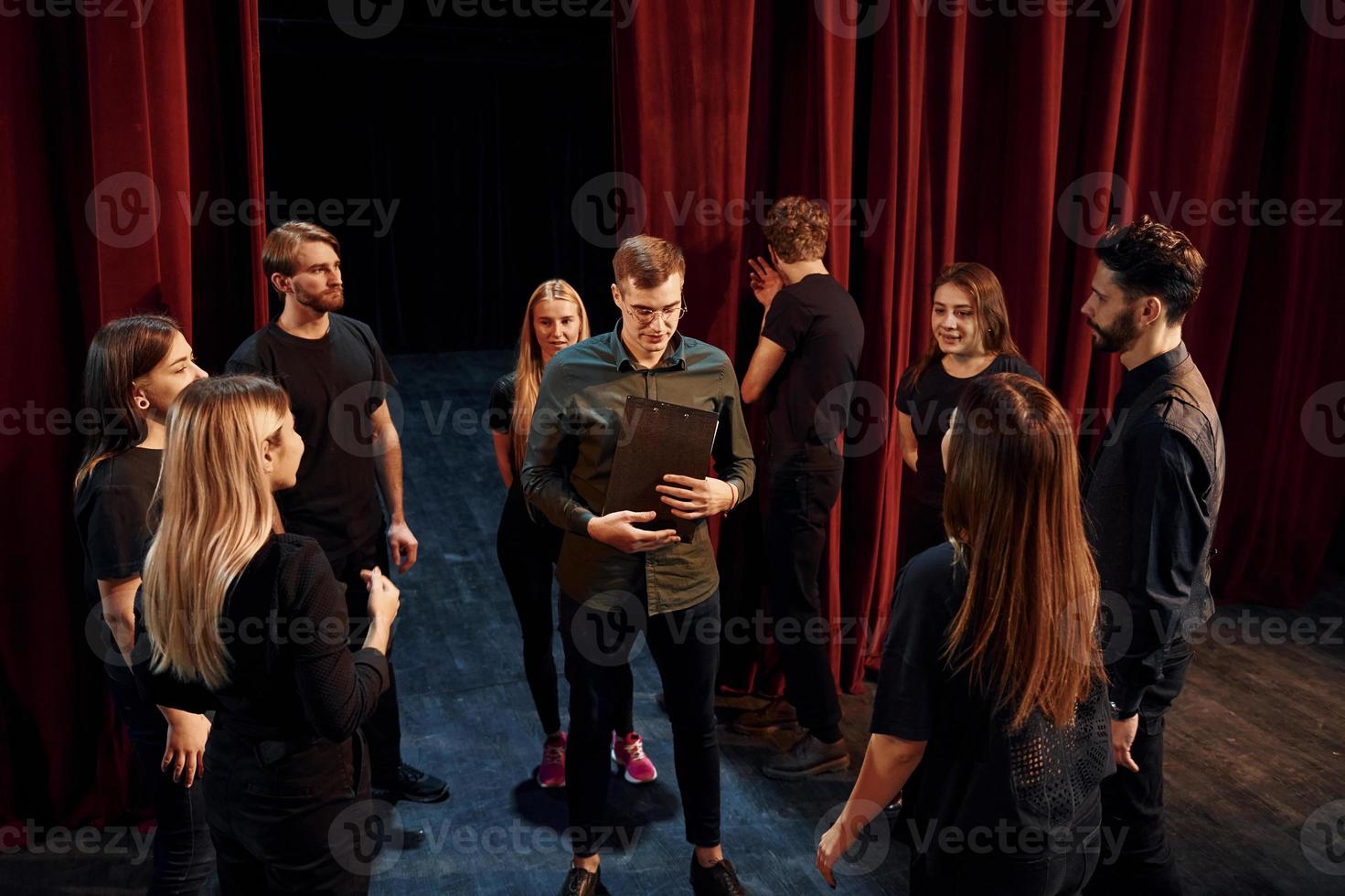 práctica en curso. grupo de actores con ropa de color oscuro ensayando en el teatro foto