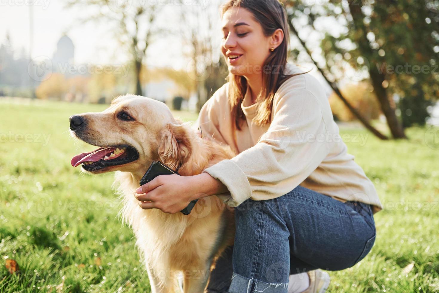 Embracing the pet. Young woman have a walk with Golden Retriever in the park photo