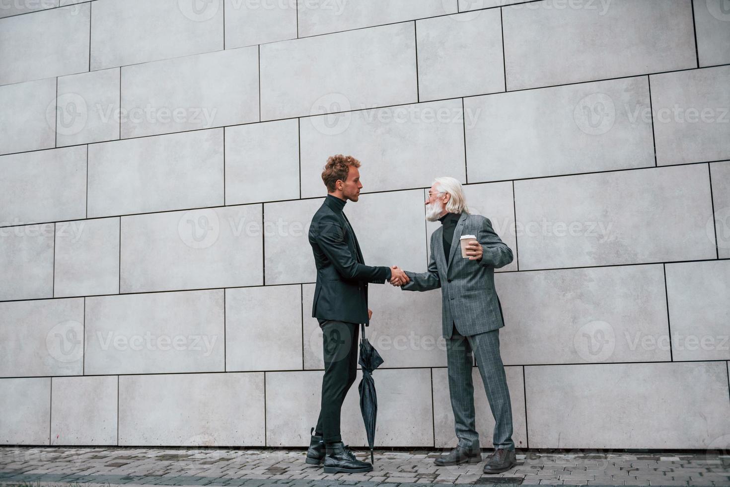 teniendo un encuentro. un joven con un anciano vestido con ropa elegante está juntos al aire libre. concepción del negocio foto