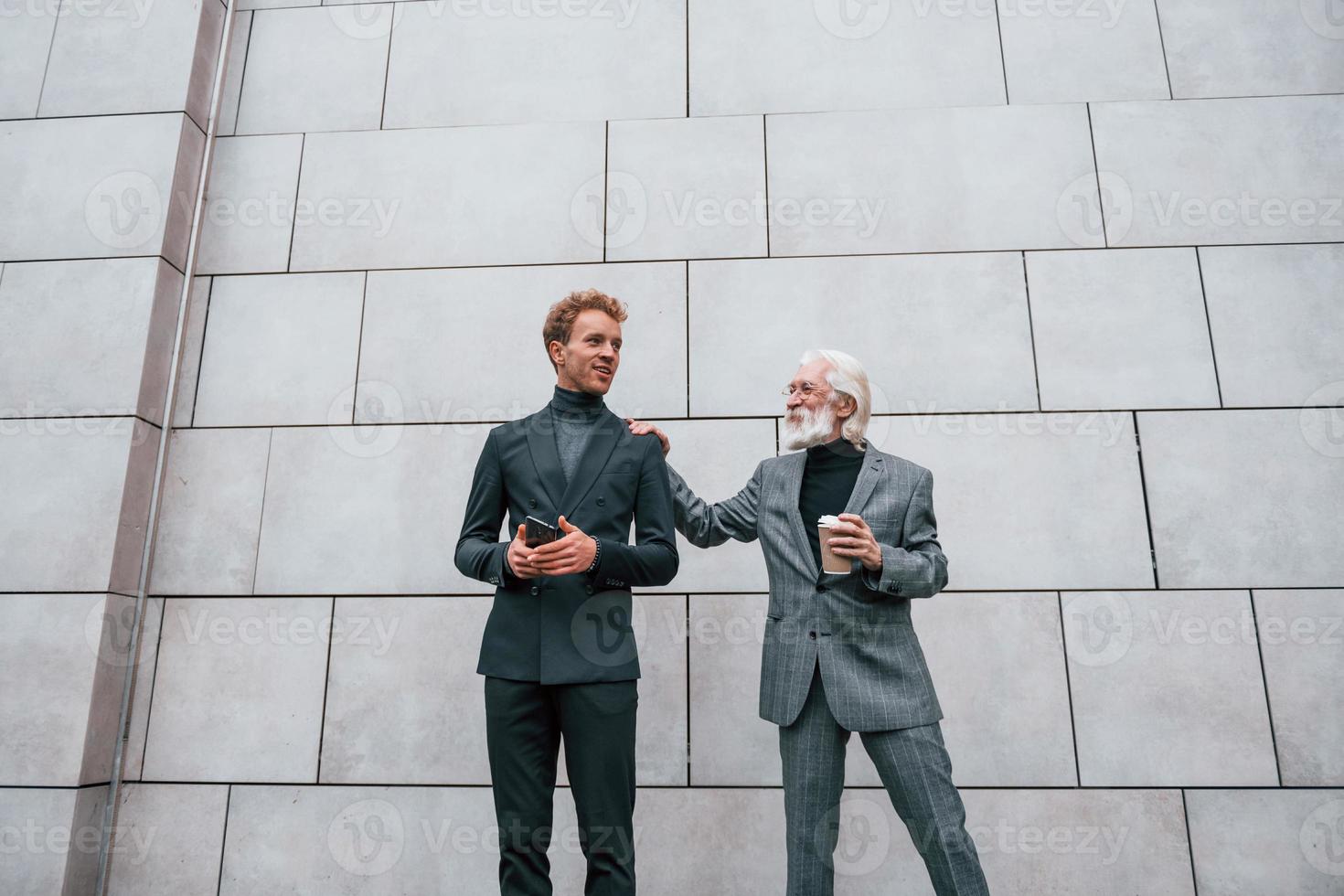 un joven con un anciano vestido con ropa elegante está juntos al aire libre. concepción del negocio foto