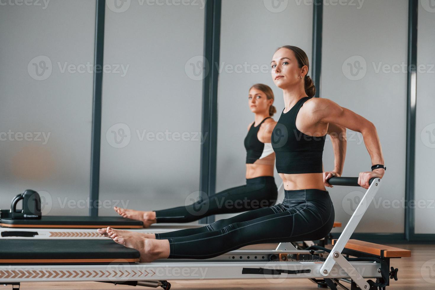 fuerza de las manos. dos mujeres con ropa deportiva y con cuerpos delgados tienen un día de yoga en el interior juntas foto