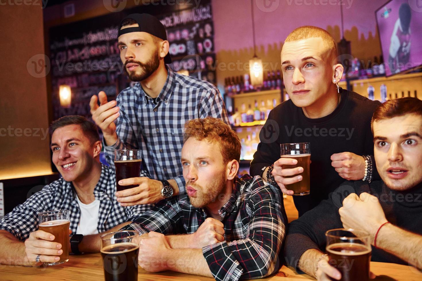 Soccer fans celebrating victory. Group of people together indoors in the pub have fun at weekend time photo