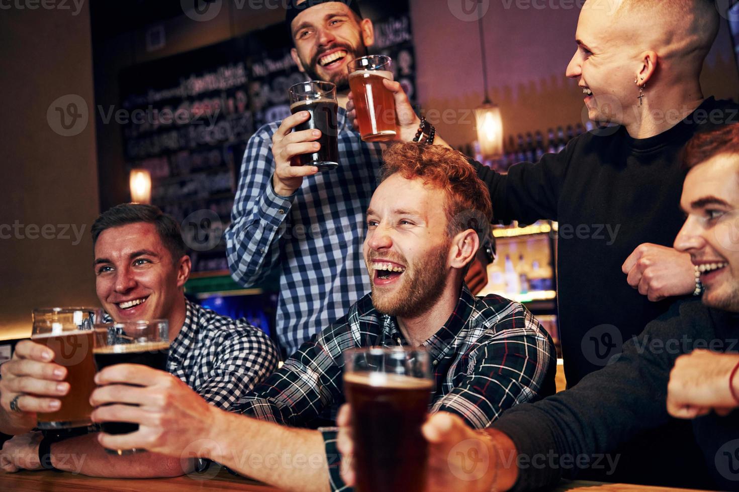 Soccer fans celebrating victory. Group of people together indoors in the pub have fun at weekend time photo