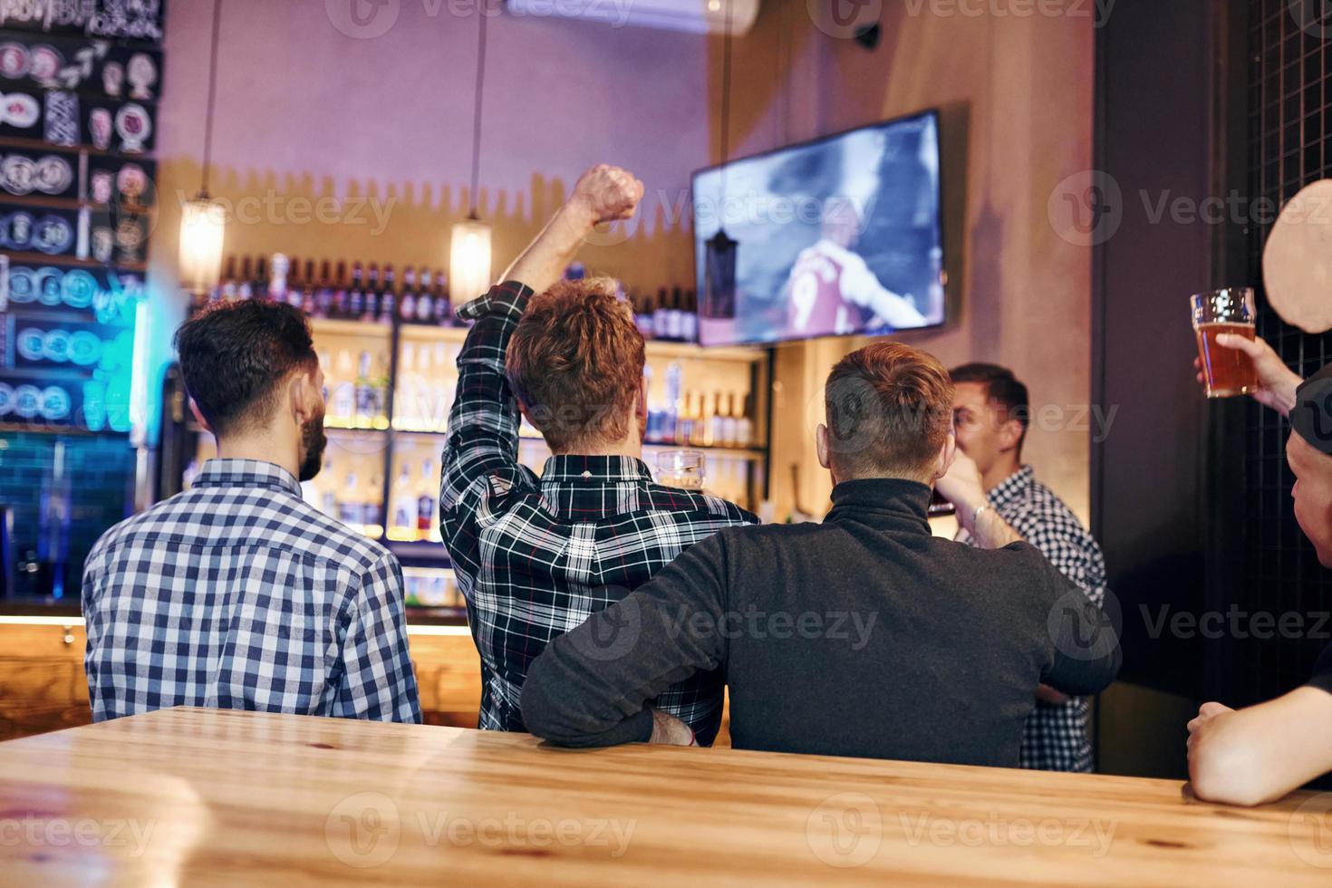 Football fans watching TV. Group of people together indoors in the pub have fun at weekend time photo