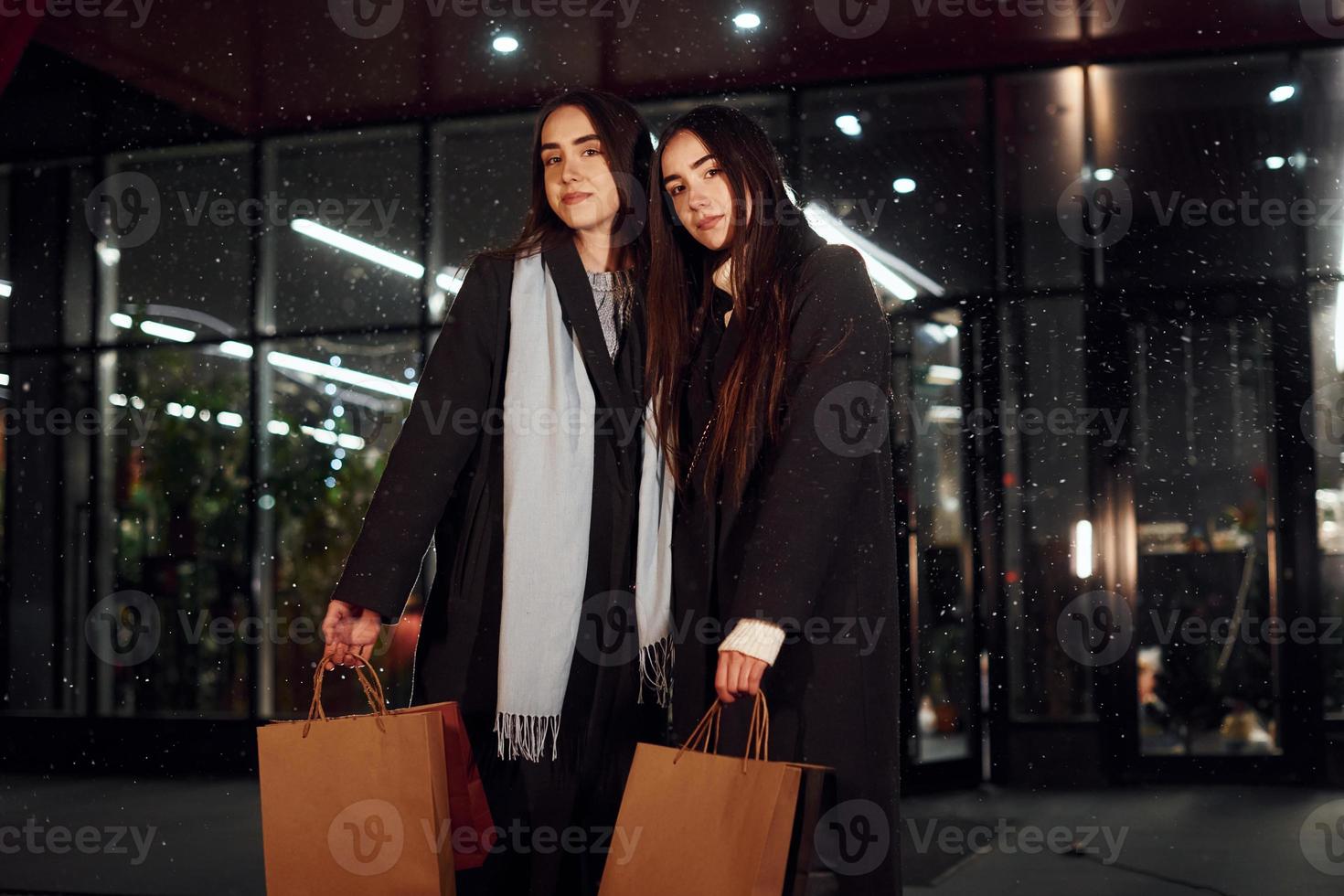 Walks with packages. Just from shopping. Happy sisters twins spends Christmas holidays together outdoors. Conception of new year photo