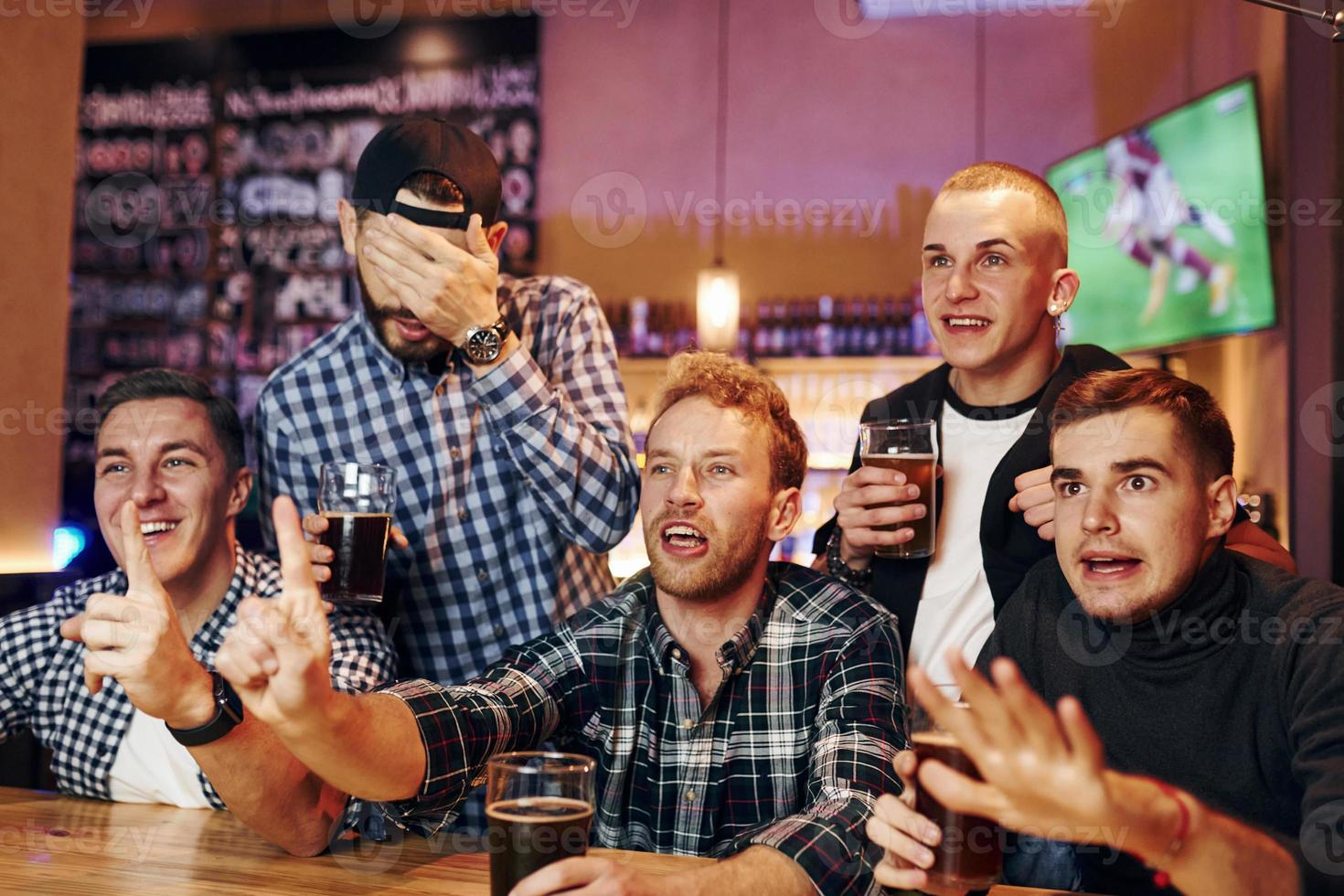 Football fans watching TV. Group of people together indoors in the pub have fun at weekend time photo