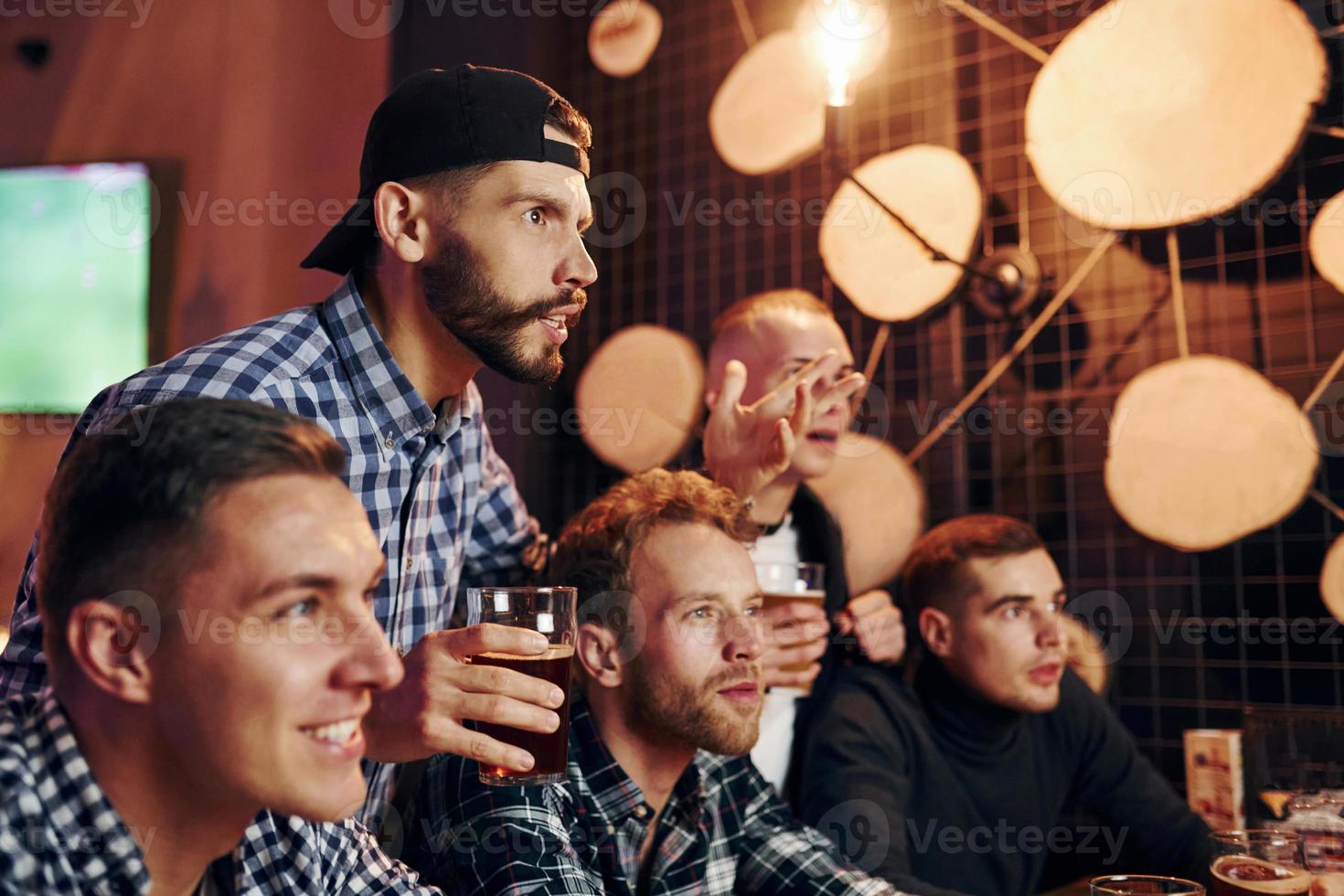 Soccer fans celebrating victory. Group of people together indoors in the pub have fun at weekend time photo