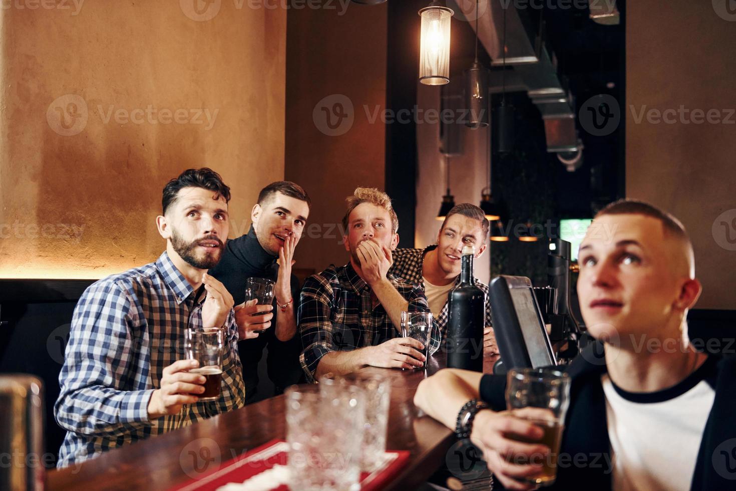 Expressive people watching soccer. Group of people together indoors in the pub have fun at weekend time photo