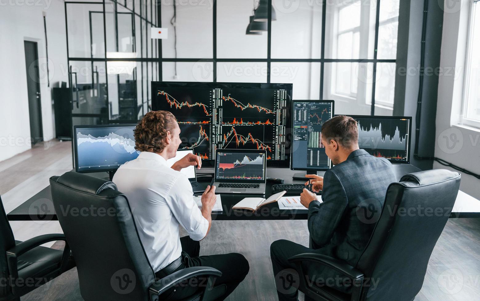 Conception of teamwork. Team of stockbrokers works in modern office with many display screens photo