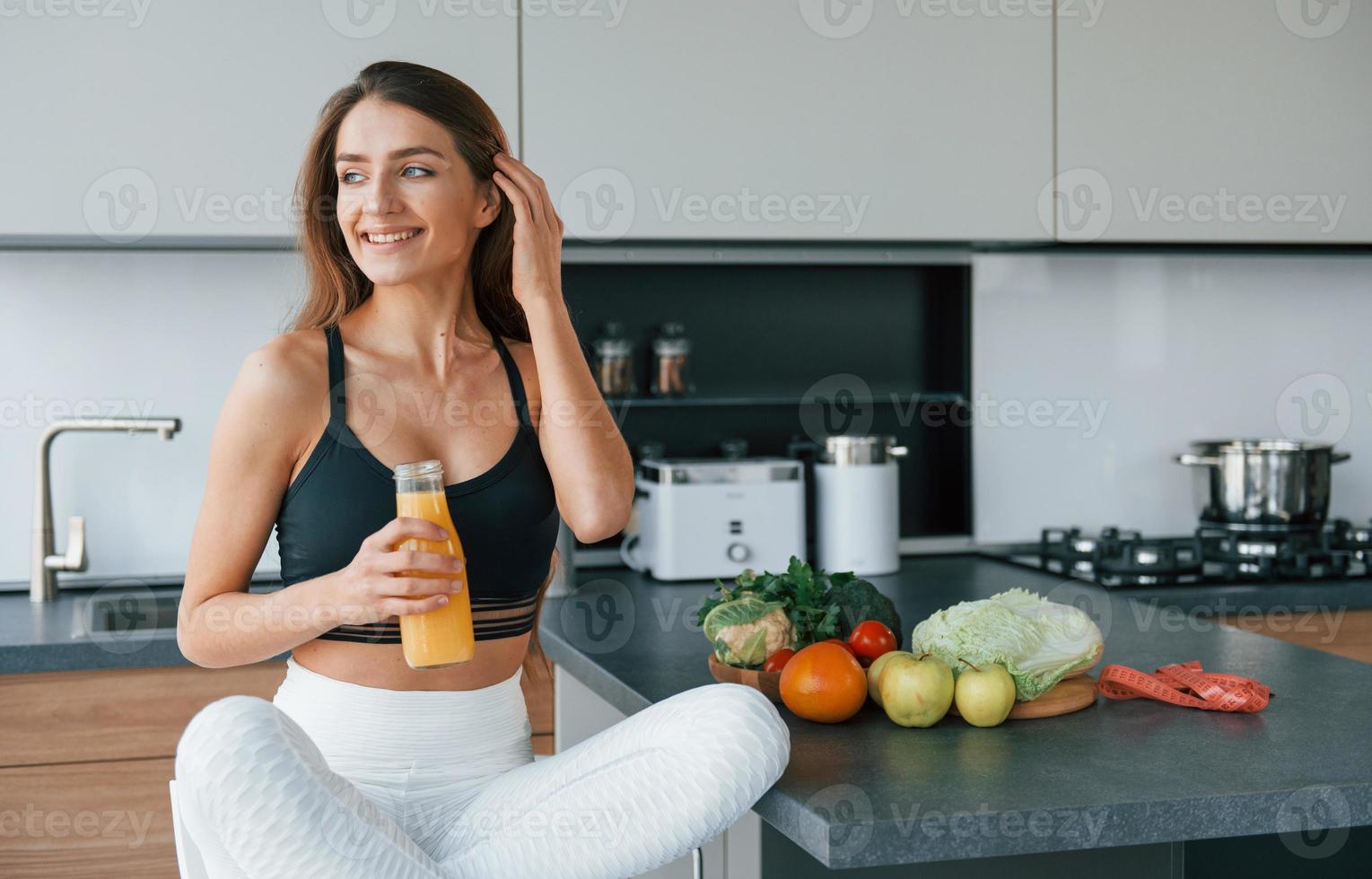 con jugo de naranja fresco. joven europea está en el interior de la cocina con comida saludable foto