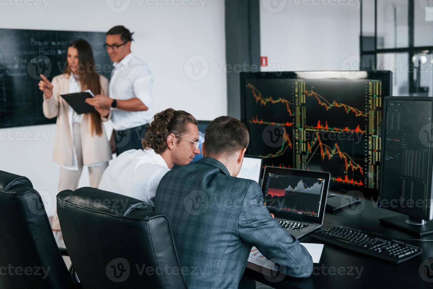 Attention to details. Team of stockbrokers works in modern office with many display screens photo