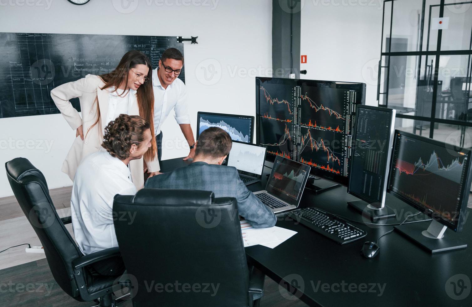 Attention to details. Team of stockbrokers works in modern office with many display screens photo