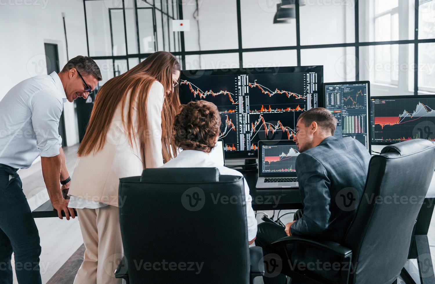 Attention to details. Team of stockbrokers works in modern office with many display screens photo