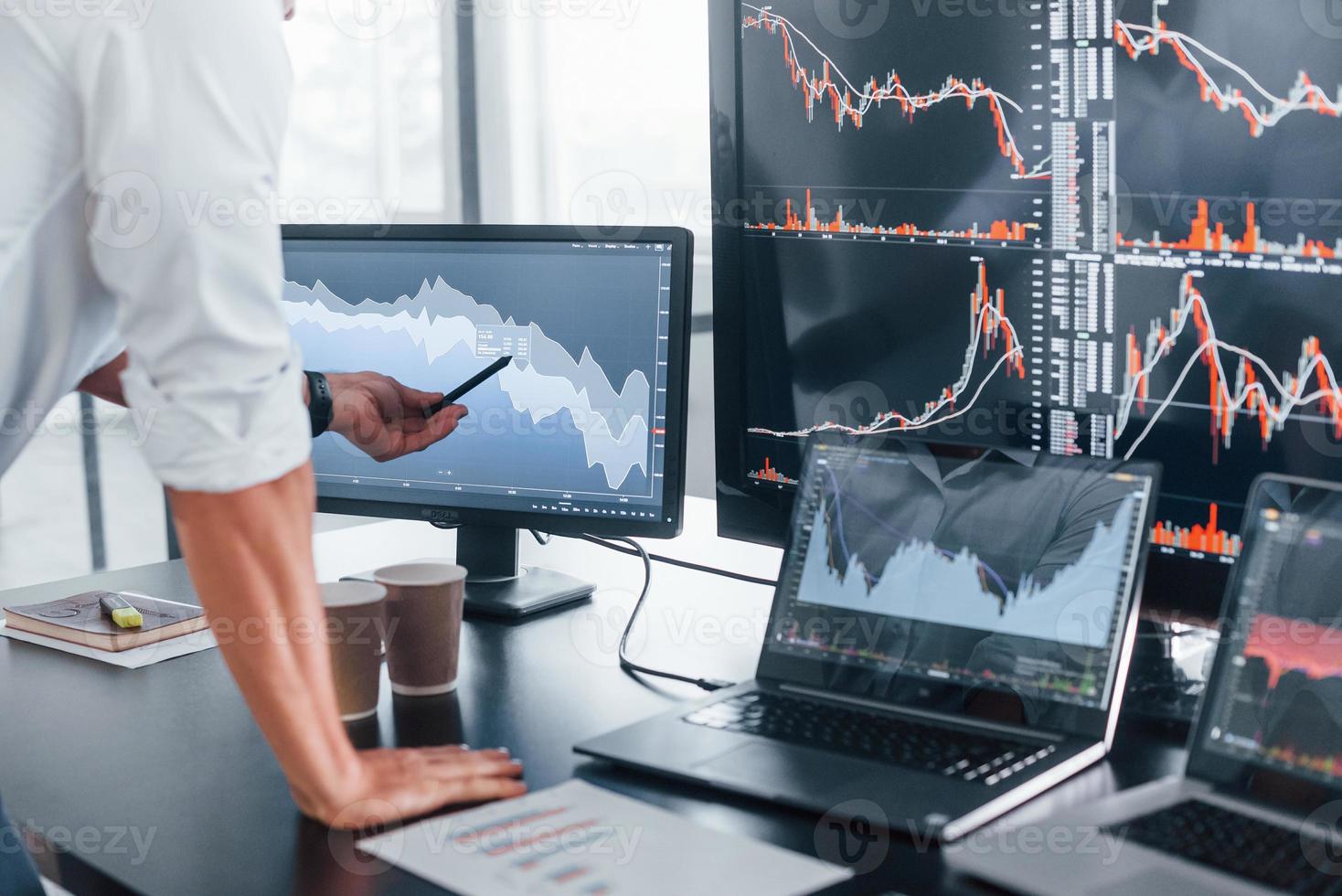 Close up view of man's hand that points at part of stock graph on display photo