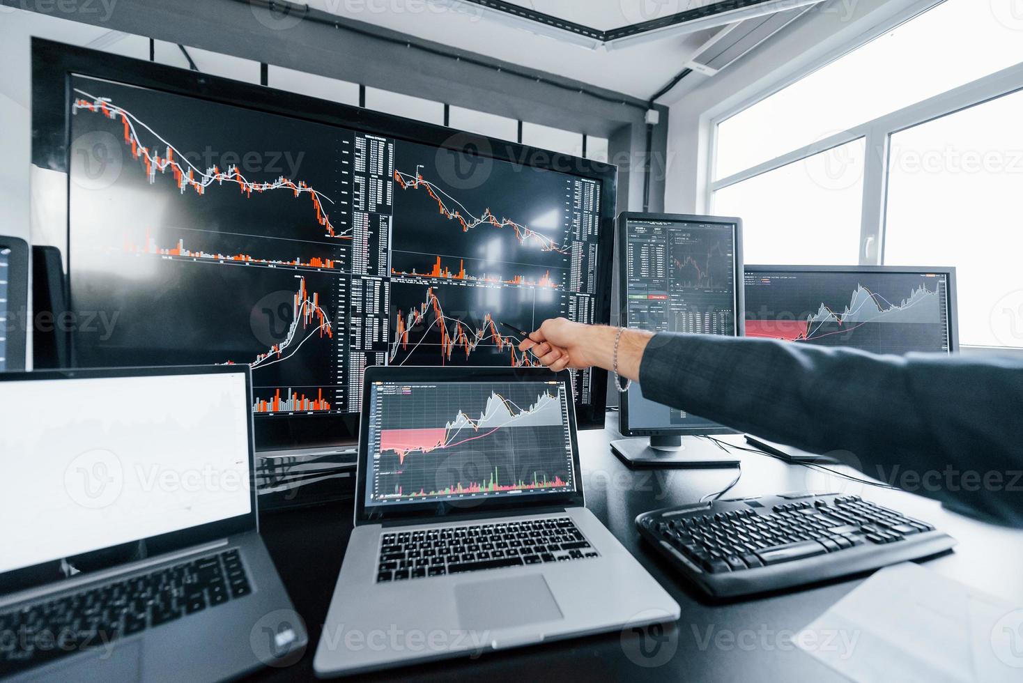 Close up view of man's hand that points at part of stock graph on display photo