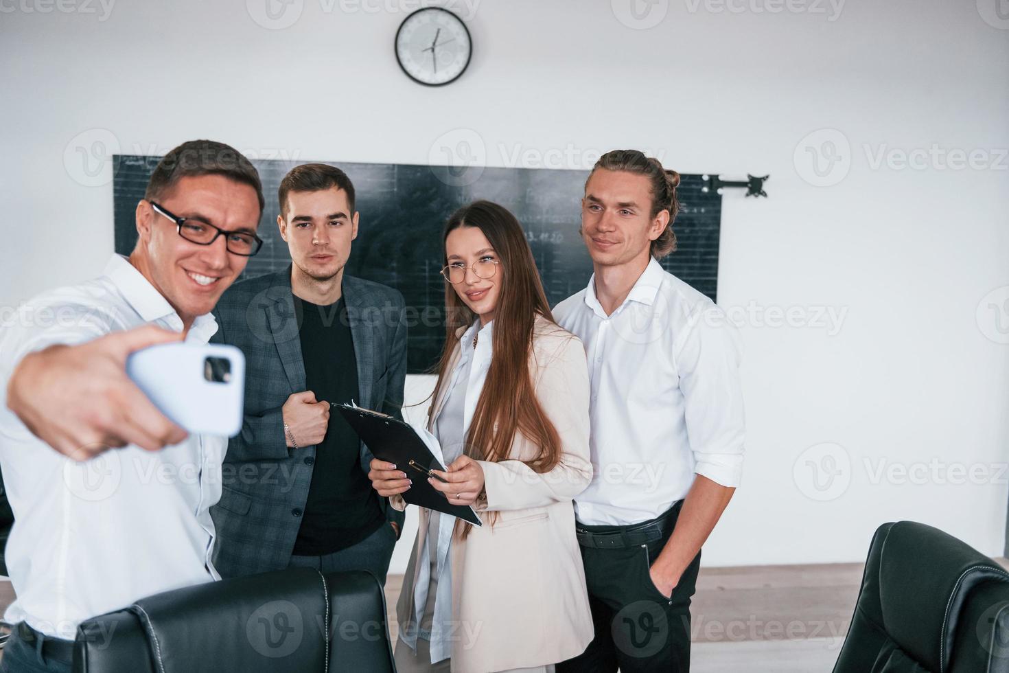 Making selfie. Group of young smart people that standing near blackboard in office photo