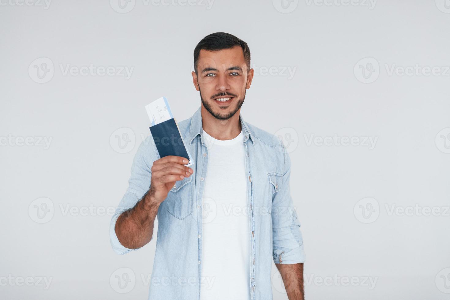 Tourist with ticket. Young handsome man standing indoors against white background photo