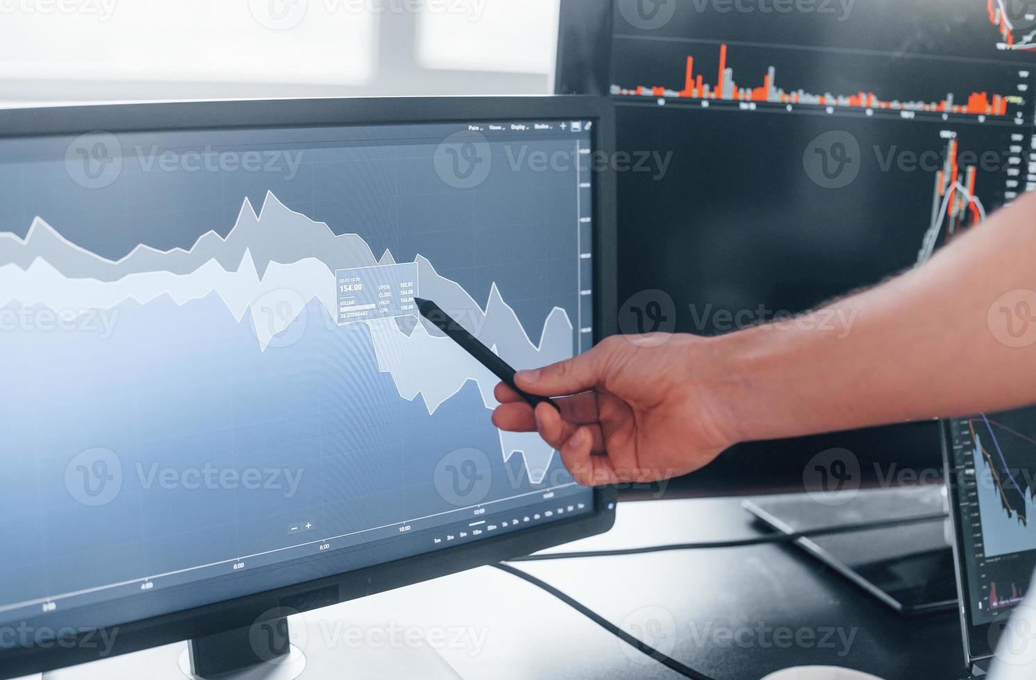 Close up view of man's hand that points at part of stock graph on display photo
