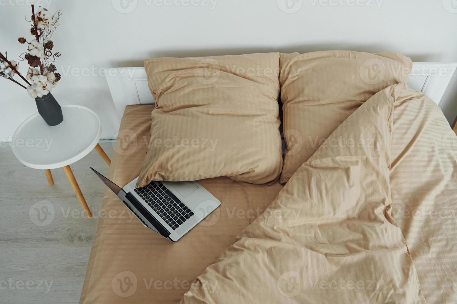 la computadora portátil está en la cama. interior y diseño de hermoso dormitorio moderno durante el día foto