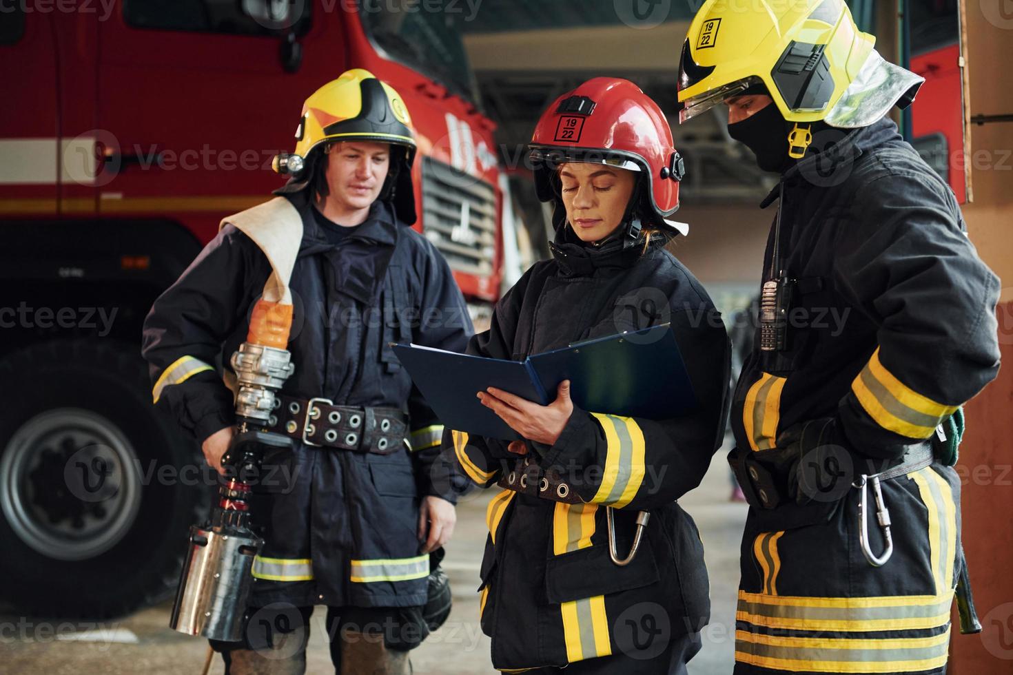 With notepad. Group of firefighters in protective uniform that is on station photo