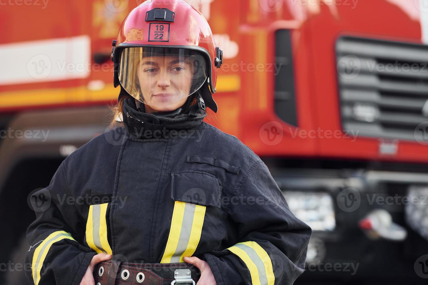 Female firefighter in protective uniform standing near truck photo