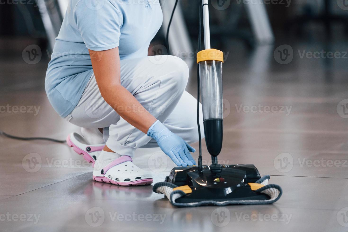 Close up view of woman that uses vacuum cleaner indoor in modern office photo