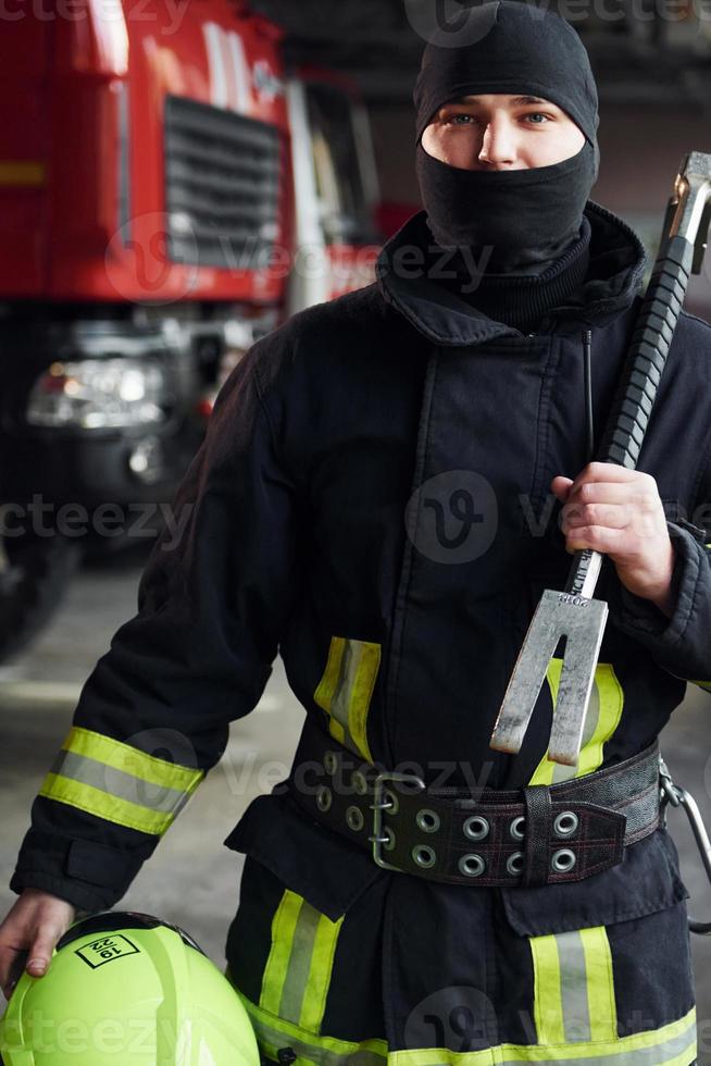 Male firefighter in protective uniform standing near truck photo