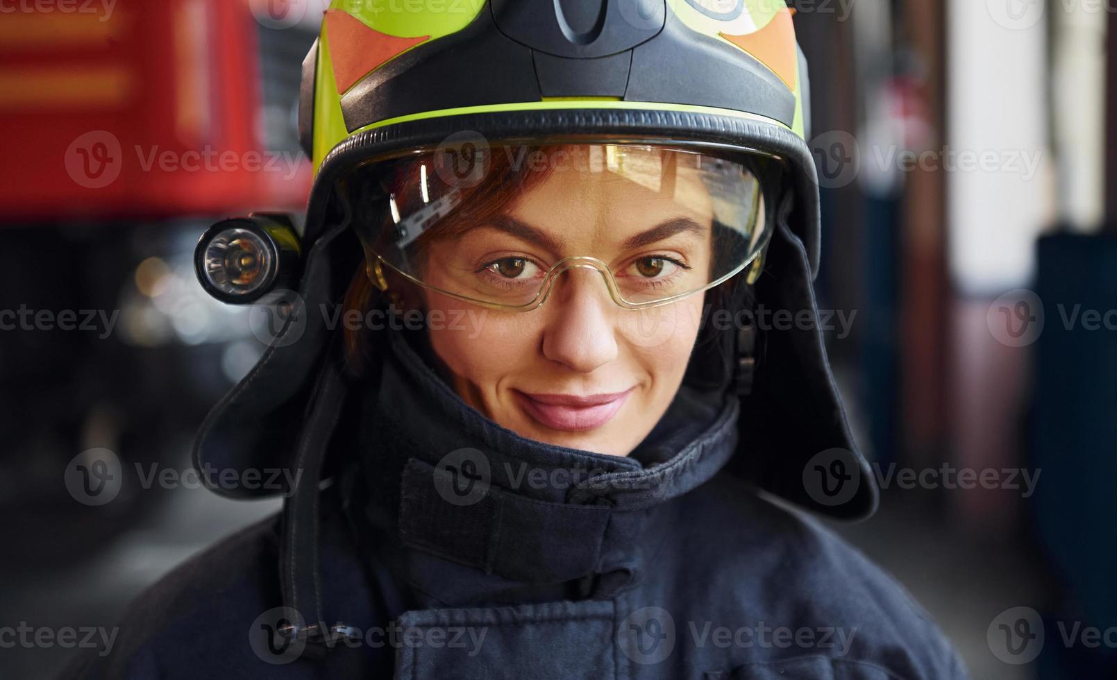 Close up view. Female firefighter in protective uniform standing near truck photo
