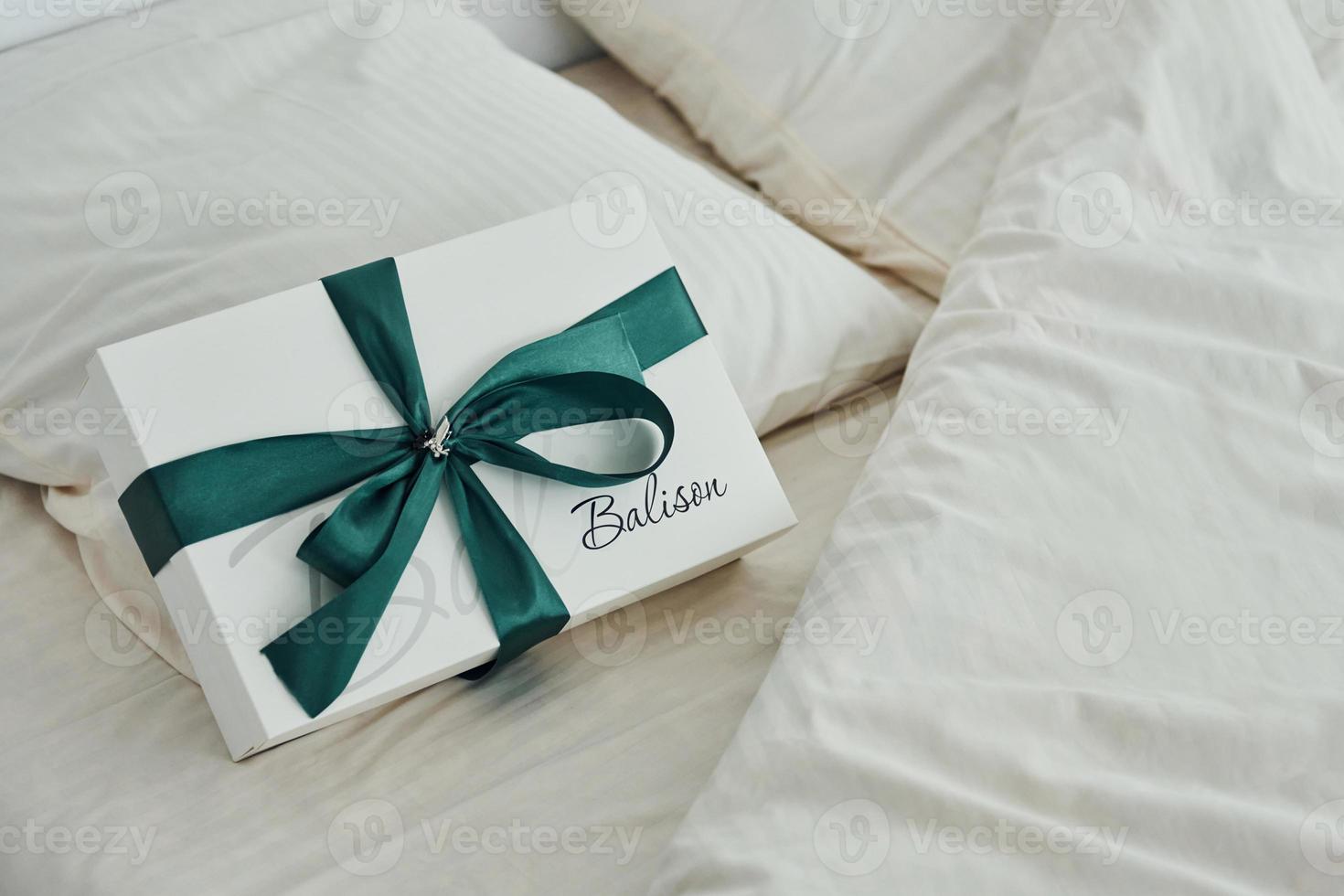 Gift box is on the white bed. Interior and design of beautiful modern bedroom at daytime photo