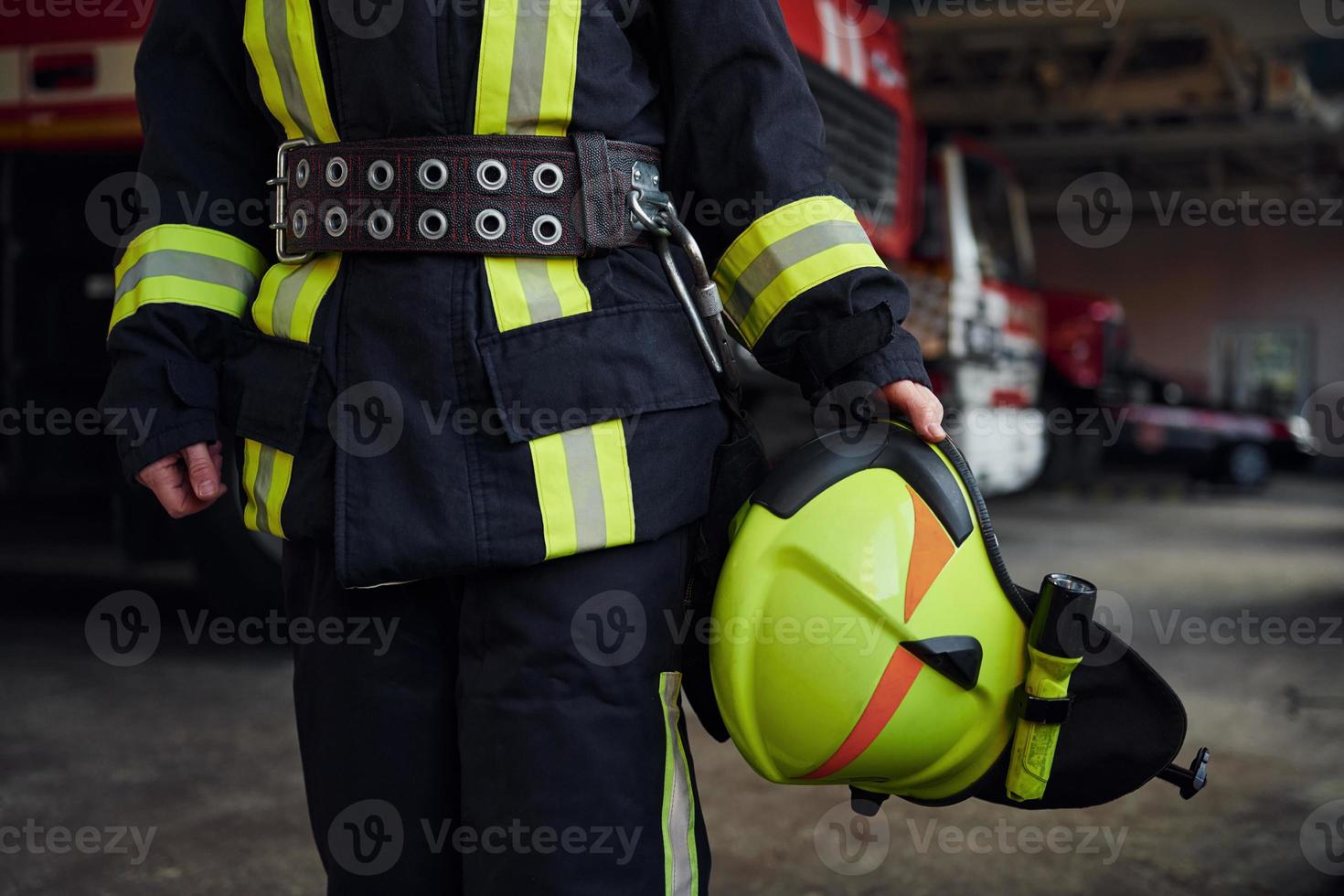 Close up view. Female firefighter in protective uniform standing near truck photo