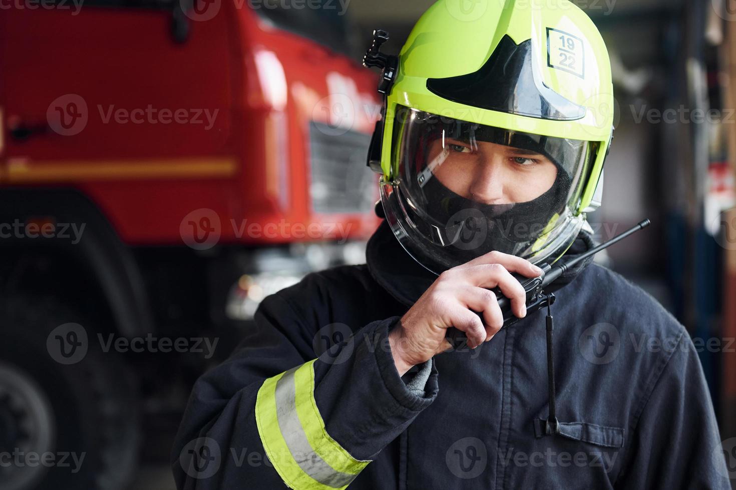 Male firefighter in protective uniform standing near truck photo