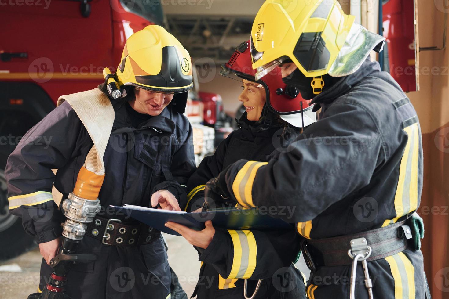 With notepad. Group of firefighters in protective uniform that is on station photo