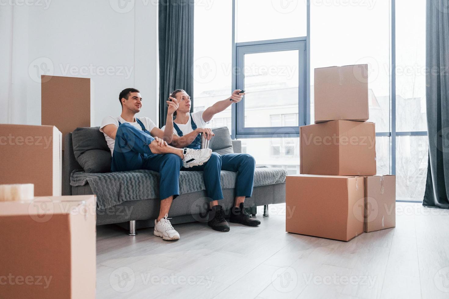 Two young movers in blue uniform working indoors in the room photo