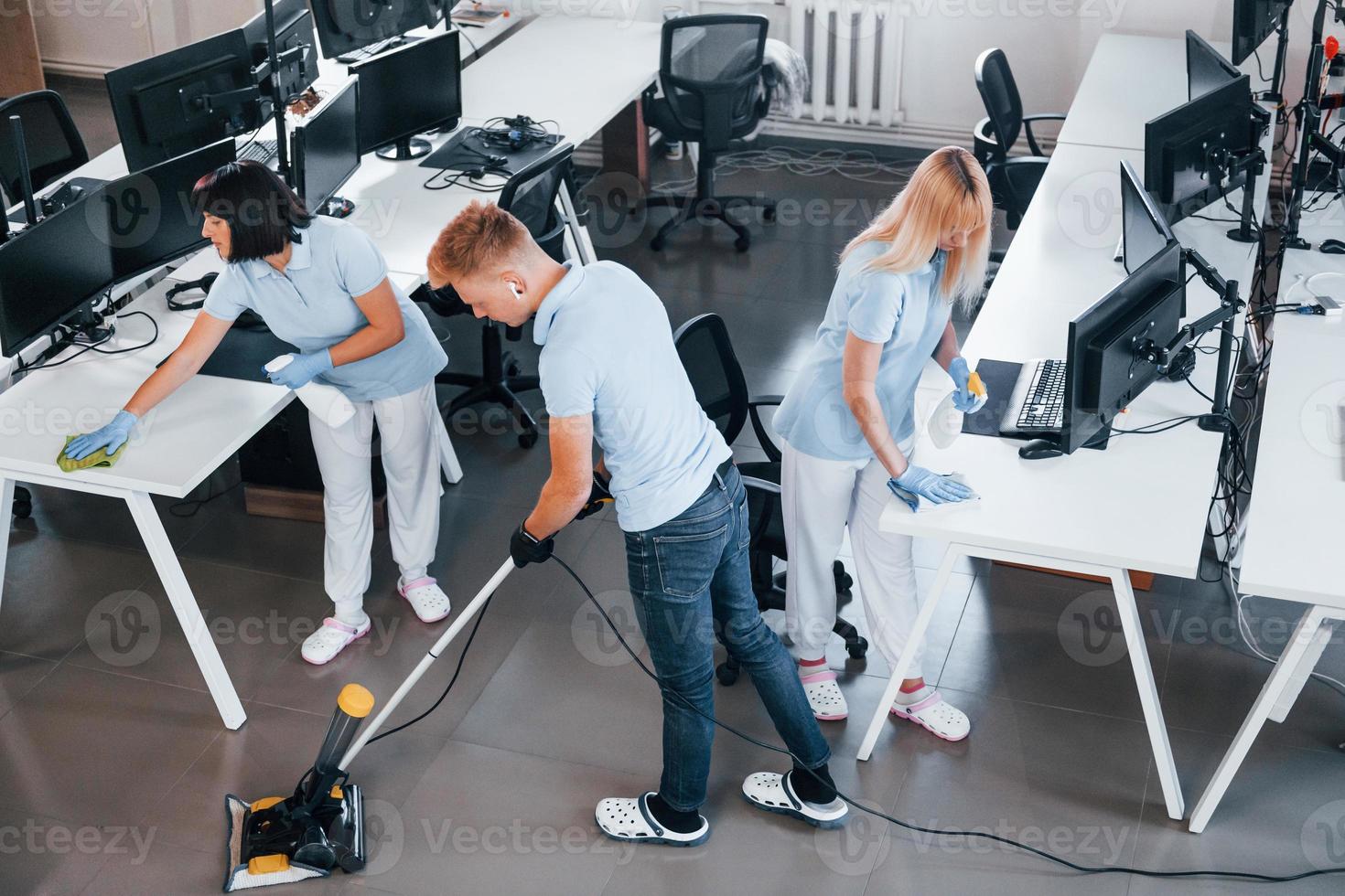 Concentrated at job. Group of workers clean modern office together at daytime photo