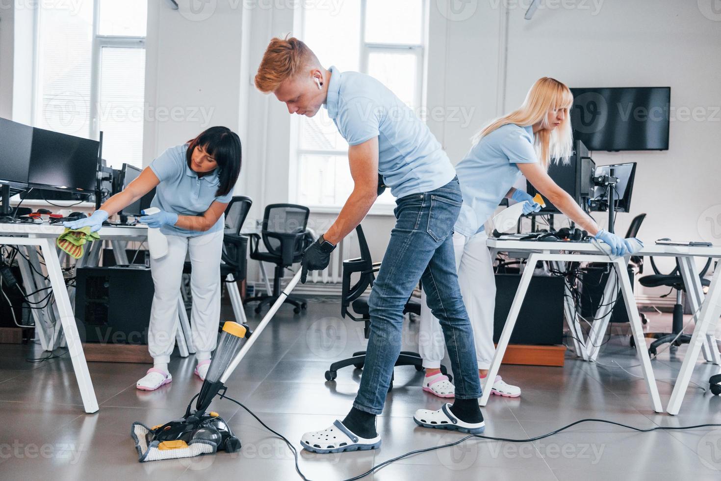 Concentrated at job. Group of workers clean modern office together at daytime photo