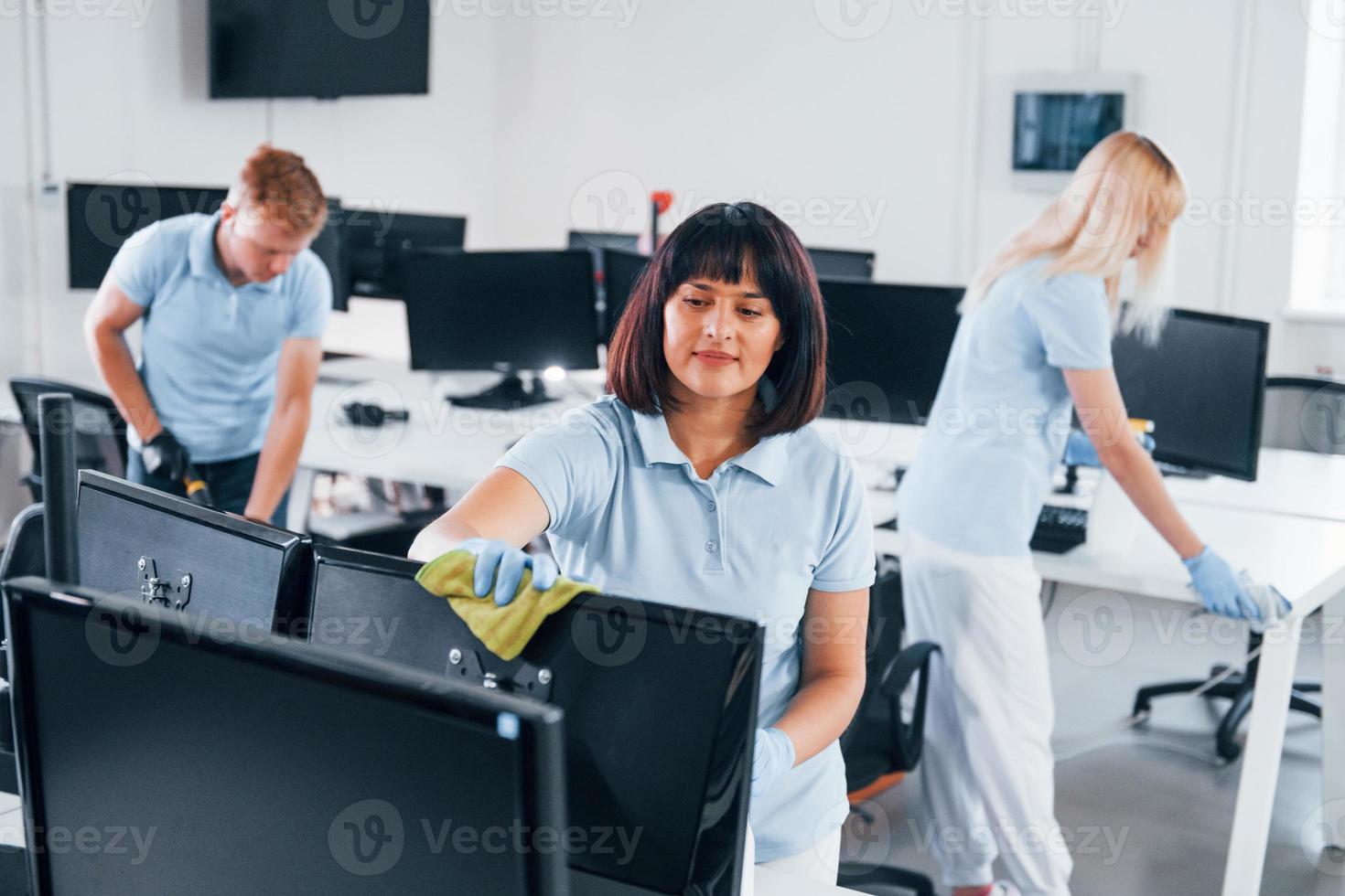 Group of workers clean modern office together at daytime photo